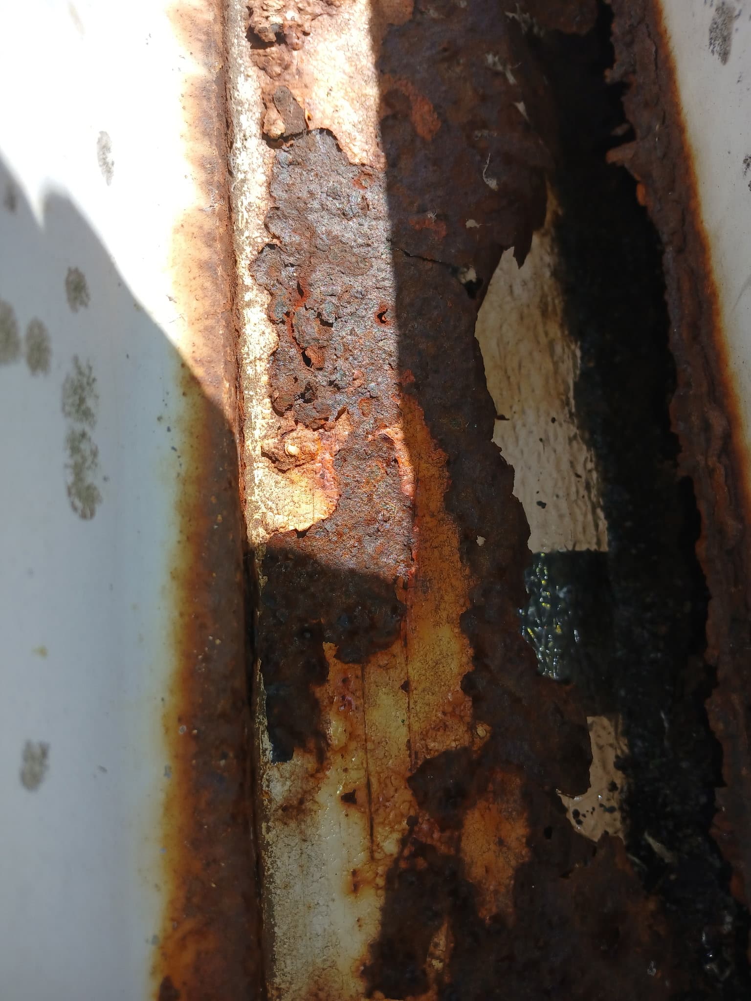 Before example — close-up of failing gutter with rust pitting and pinholes