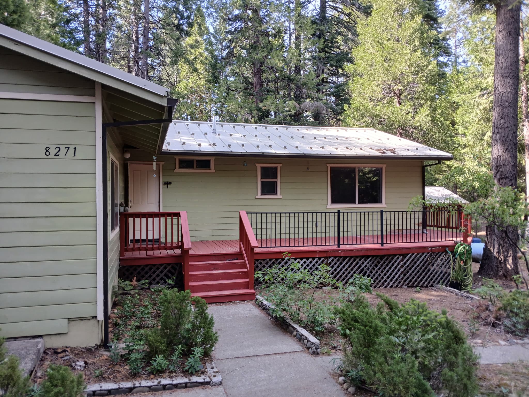 Sage green cabin tucked into the pines with new gutters in Shasta Lake