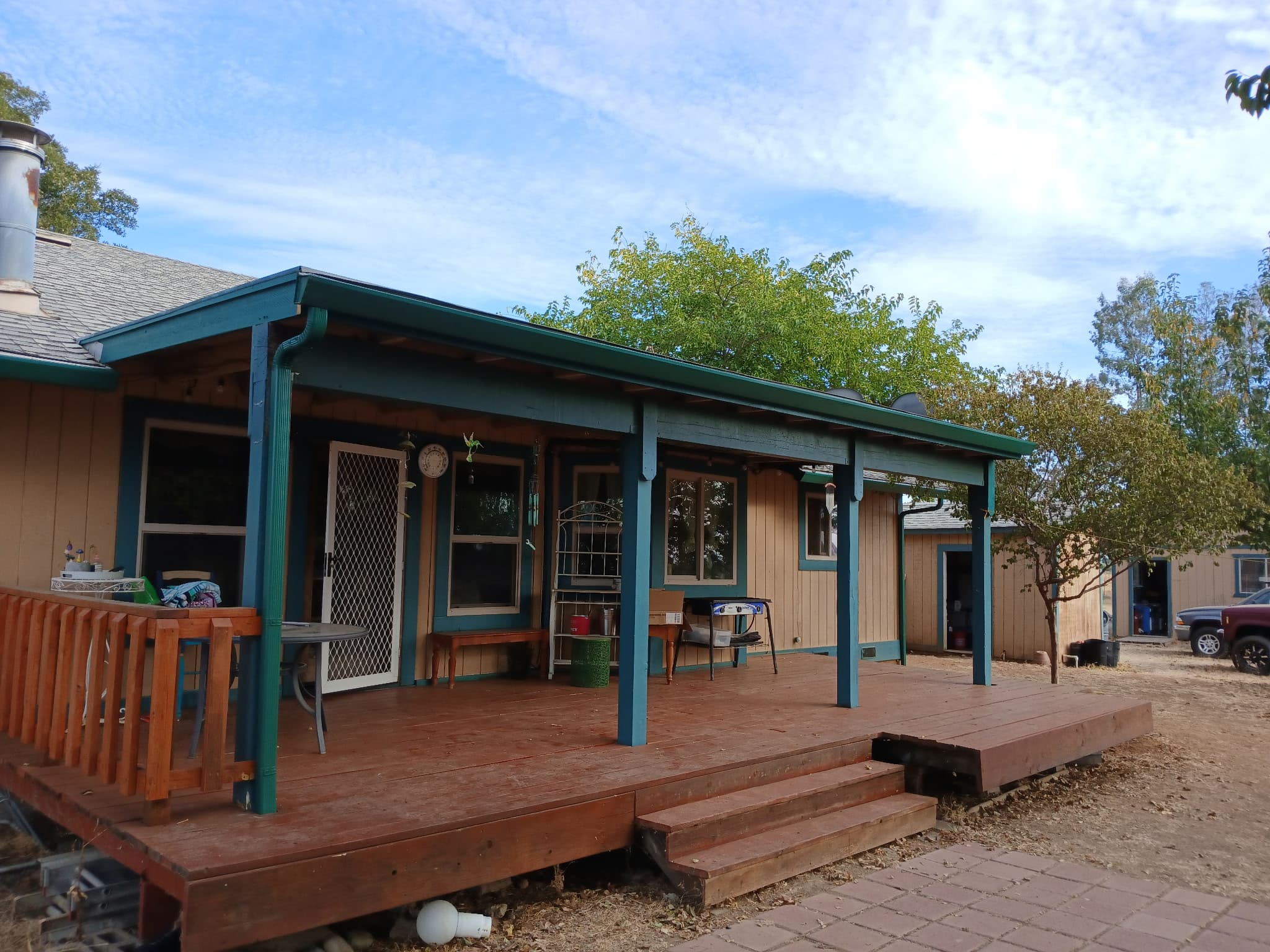 Teal-trimmed wraparound porch cabin with seamless gutters in Palo Cedro